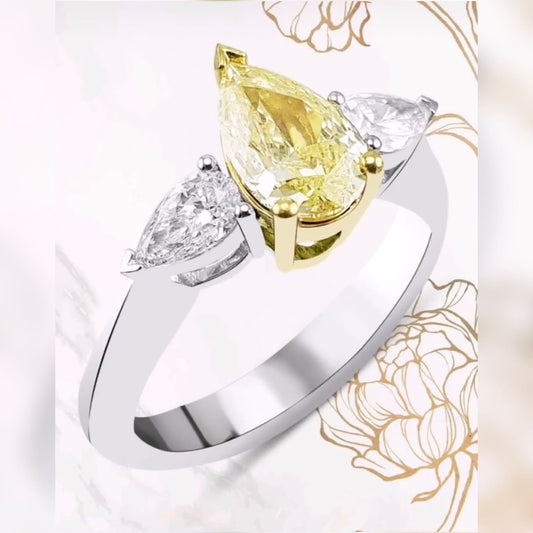 Великолепен годежен пръстен с жълт диамант и два бели диаманта. Този годежен пръстен капка е с инвестиционна стойност, заради своя жълт диамант 1 карат с борсов сертификат.
